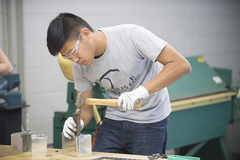 A student works at a project on a workbench.